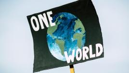 لافتة بها كرة أرضية تقول عالم واحد