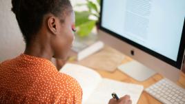 Freelancer Woman writing on notebook in front of a computer